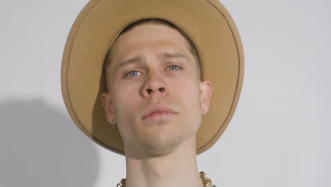 Close-Up-Portrait-Of-Young-Man-With-Big-Hat-Posing-And-Touching-His-Face-While-Looking-At-Camera