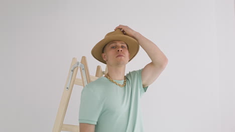 Young-Man-Putting-A-Hat-On-A-Ladder