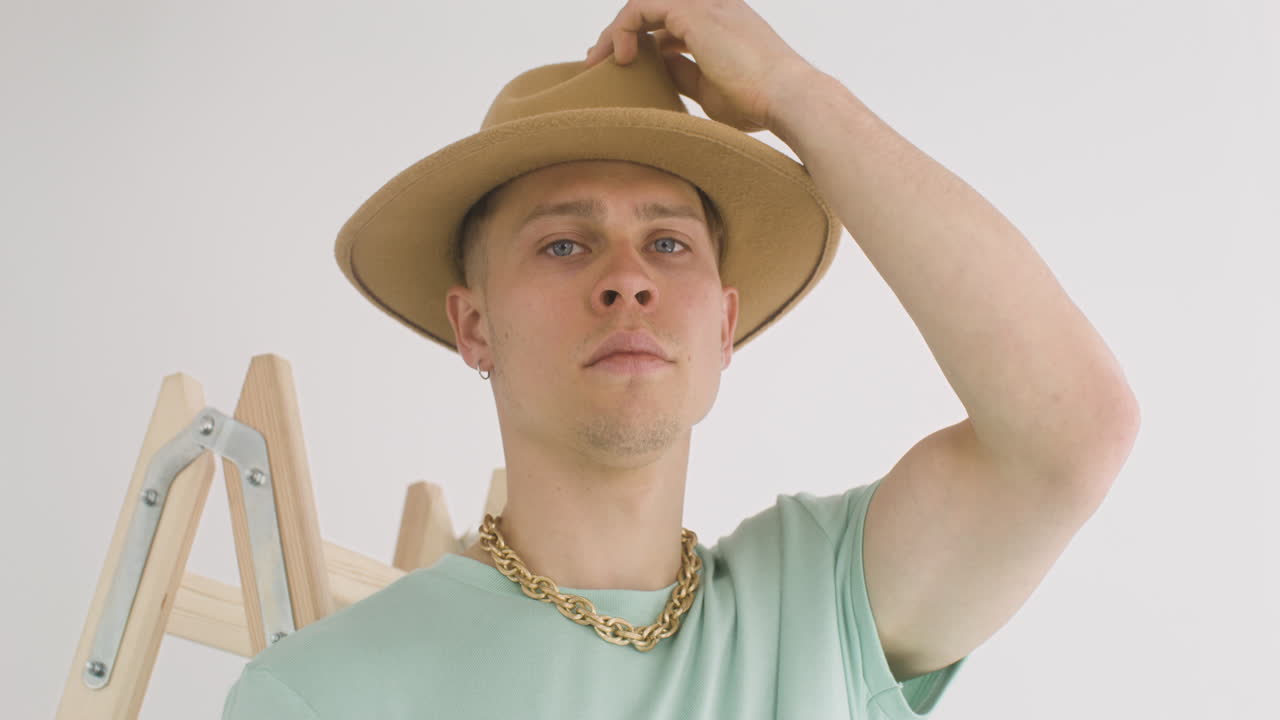 free-stock-video-handsome-man-on-a-ladder-putting-his-hat-on