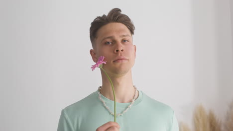 Young-Male-Model-In-Green-T-Shirt-Holding-Flower-Next-To-His-Face