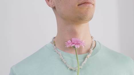 Close-Up-Young-Man-With-Necklace-And-T-Shirt-Holding-A-Flower-1