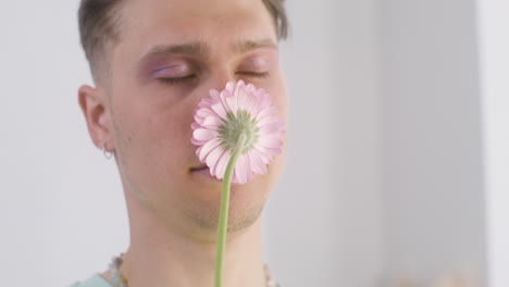 Young-Man-Holding-And-Smelling-Pink-Flower
