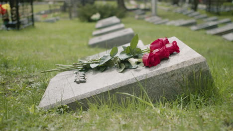 Side-View-Of-Red-Roses-On-Tombstone-In-A-Gravevard