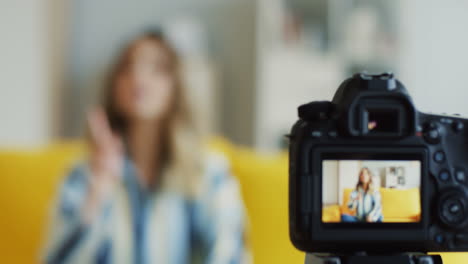 Close-Up-Of-The-Camera-Screen-On-Which-Young-Female-Blogger-Talking-To-Her-Followers-While-Sitting-On-A-Yellow-Sofa-In-A-Modern-Apartment