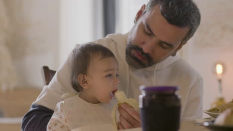 Handsome-Bearded-Dad-Feeding-His-Baby-Daughter-With-Banana-1