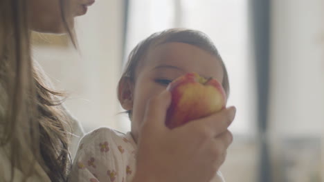Nahaufnahme-Einer-Mutter,-Die-Ihre-Kleine-Tochter-Hält-Und-Morgens-Zusammen-Einen-Apfel-Isst