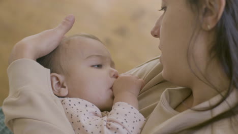 Close-Up-Shot-Of-An-Adorable-Baby-Girl-Sucking-Her-Thumb-And-Falling-Asleep-While-Her-Mother-Holding-Her,-Singing-A-Lullabay-And-Stroking-Her-Hair-Gently-1