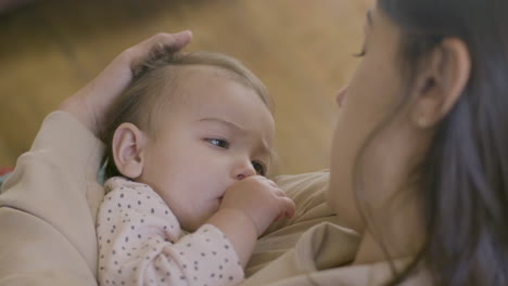 Close-Up-Shot-Of-An-Adorable-Baby-Girl-Sucking-Her-Thumb-And-Falling-Asleep-While-Her-Mother-Holding-Her,-Singing-A-Lullabay-And-Stroking-Her-Hair-Gently-2