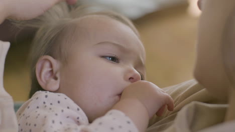 Close-Up-Shot-Of-An-Adorable-Baby-Girl-Sucking-Her-Thumb-And-Falling-Asleep-While-Her-Mother-Holding-Her,-Singing-A-Lullabay-And-Stroking-Her-Hair-Gently-3