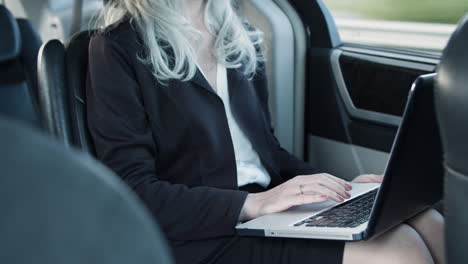 Businesswoman-Using-Laptop-Inside-The-Moving-Car