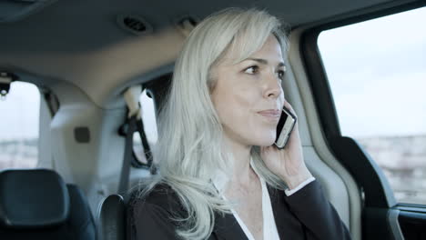 Gray-Haired-Businesswoman-Talking-On-Phone-Inside-A-Car