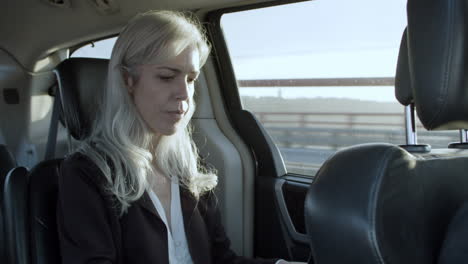 Gray-Haired-Businesswoman-Working-On-Laptop-In-Car