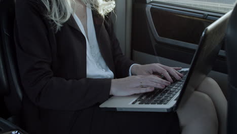 Gray-Haired-Woman-Working-On-Laptop-In-Car
