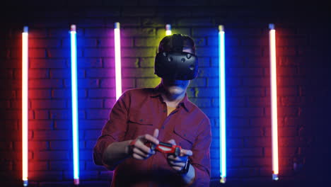 Man-In-Vr-Glasses-And-Playing-Videogame-With-Joystick-In-A-Room-With-Colorful-Neon-Lamps-On-The-Wall