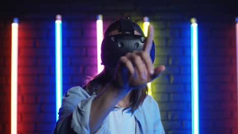 Close-Up-View-Of-Young-Man-In-Vr-Glasses-Tapping-And-Scrolling-In-Front-Of-Him-In-The-Air-In-A-Room-With-Colorful-Neon-Lamps-On-The-Wall