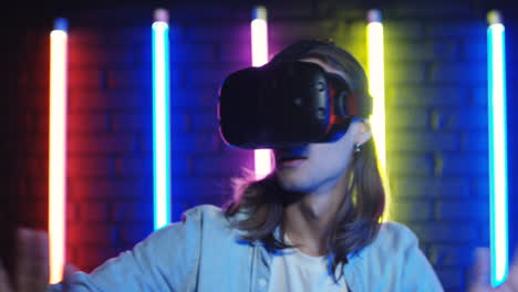 Close-Up-View-Of-Young-Man-In-Vr-Glasses-And-Moving-Like-Scared-In-A-Room-With-Colorful-Neon-Lamps-On-The-Wall