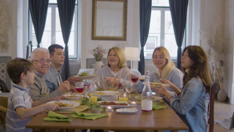 Porträt-Einer-Glücklichen-Familie,-Die-Am-Tisch-Sitzt,-Posiert-Und-Bei-Einem-Festlichen-Abendessen-Zu-Hause-In-Die-Kamera-Schaut