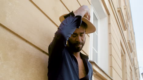 Hombre-Afro-Caribeño-Poniéndose-Su-Sombrero-Panamá-Mientras-Se-Apoya-En-La-Pared-Con-Una-Pierna-En-La-Calle-1-Del-Casco-Antiguo