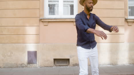 Happy-Afro-Caribbean-Man-With-Panama-Hat-Dancing-Latin-Choreographies-Alone-In-Street