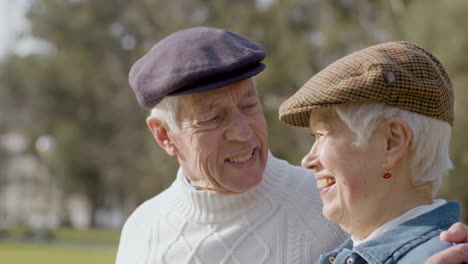 Entzückendes-älteres-Paar,-Das-Sich-Küsst-Und-Redet,-Während-Es-Gemeinsam-Den-Sonnigen-Tag-Im-Park-Genießt