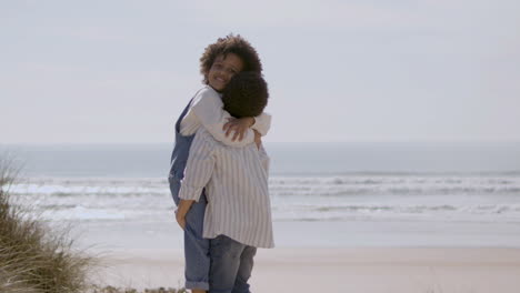 Cute-American-Boy-Holding-And-Hugging-His-Little-Sister-At-The-Beach-On-A-Sunny-Day