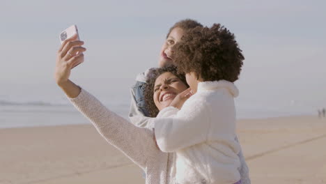 Glückliche-Amerikanische-Mutter-Und-Zwei-Kinder,-Die-Selfie-Machen-Und-Lustige-Gesichter-Vor-Der-Kamera-Machen,-Während-Sie-Zeit-An-Der-Meeresküste-Verbringen