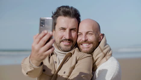 Vorderansicht-Eines-Glücklichen-Schwulen-Paares,-Das-Am-Strand-Ein-Selfie-Macht