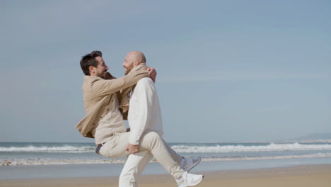 Happy-Homosexual-Man-Jumping-Into-Partner's-Arms-And-Kissing-Him-On-The-Beach
