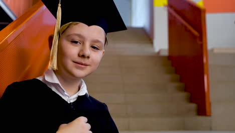 Portrait-Of-A-Happy-Preschool-Male-Student-In-Cap-And-Gown-Holding-Graduation-Diploma-And-Looking-At-The-Camera