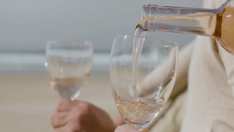 Nahaufnahme-Eines-Nicht-Erkennbaren-Mannes,-Der-Am-Strand-Wein-In-Gläser-Gießt