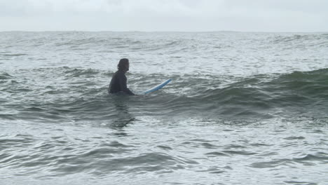 Sportive-Man-In-Wetsuit-With-Artificial-Leg-Lying-On-Surfboard-And-Swimming-In-The-Ocean