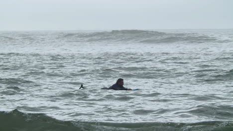 Sportive-Man-In-Wetsuit-With-Artificial-Leg-Lying-On-Surfboard-And-Swimming-In-The-Ocean-1
