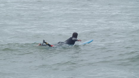 Sportive-Man-In-Wetsuit-With-Artificial-Leg-Lying-On-Surfboard-And-Swimming-In-The-Ocean-5