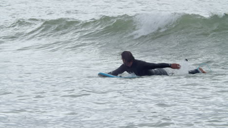 Sportive-Man-In-Wetsuit-With-Artificial-Leg-Lying-On-Surfboard-And-Swimming-In-The-Ocean-7