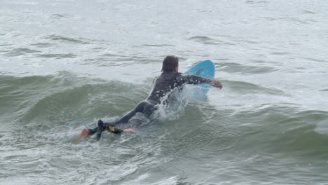 Sportive-Man-In-Wetsuit-With-Artificial-Leg-Lying-On-Surfboard-And-Swimming-In-The-Ocean-9