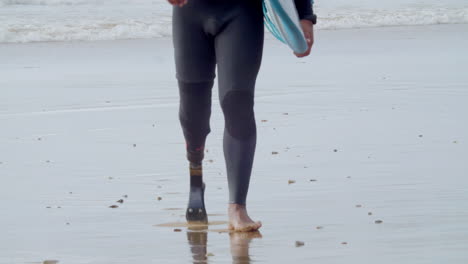Close-Up-Of-An-Unrecognizable-Man-In-Wetsuit-With-Bionic-Leg-Walking-Along-The-Seashore-1