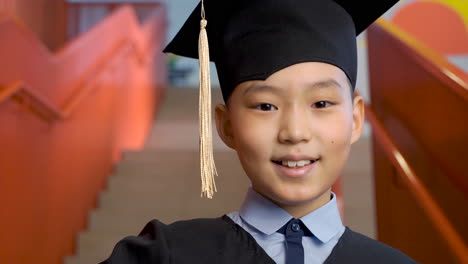 Portrait-Of-A-Happy-Preschool-Male-Student-In-Cap-And-Gown-Holding-Graduation-Diploma-And-Looking-At-The-Camera-1