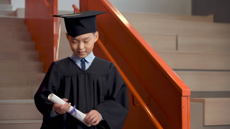 Happy-Preschool-Male-Student-In-Cap-And-Gown-Holding-Diploma-And-Celebrating-His-Graduation-1
