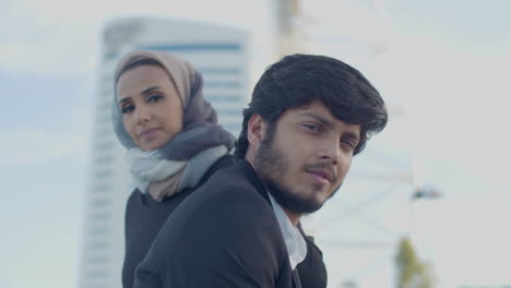 Serious-Arab-Man-And-Woman-Standing-In-City-And-Looking-At-Camera