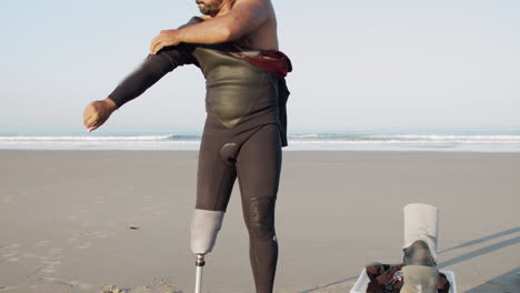 Vertikale-Bewegung-Eines-Männlichen-Surfers-Mit-Künstlichem-Bein,-Der-Einen-Neoprenanzug-Am-Strand-Trägt