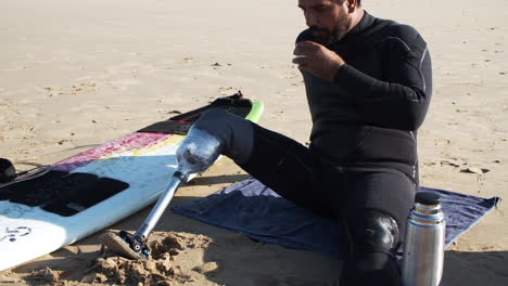 Zeitlupe-Eines-Männlichen-Surfers-Mit-Künstlichem-Bein,-Der-Tee-Am-Strand-Trinkt
