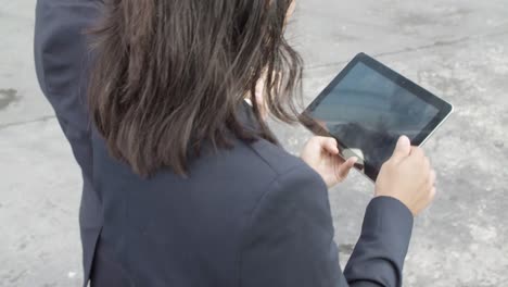 High-Angle-Of-Two-Female-Office-Colleagues-Using-Tablet-And-Watching-Content-Together-While-Walking-Outside
