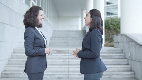 Side-View-Of-Two-Confident-Business-Colleagues-In-Suits-Standing-Outside-And-Talking