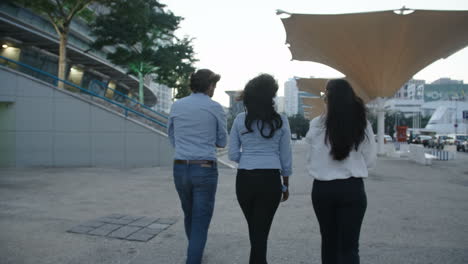 Back-View-Of-Three-Young-Business-People-Walking-In-Same-Direction,-Talking