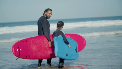Surftrainer-Mit-Künstlichem-Bein-Und-Mädchen,-Die-Surfbrett-Halten-Und-Beim-Gehen-Am-Strand-Sprechen