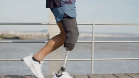 Close-Up-Of-An-Unrecognizable-Sportsman-With-Artificial-Leg-Running-Along-Embankment-In-The-Morning