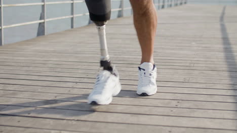 Nahaufnahme-Eines-Nicht-Erkennbaren-Sportlers-Mit-Beinprothese,-Der-Morgens-Eine-Böschung-Entlang-Läuft-1