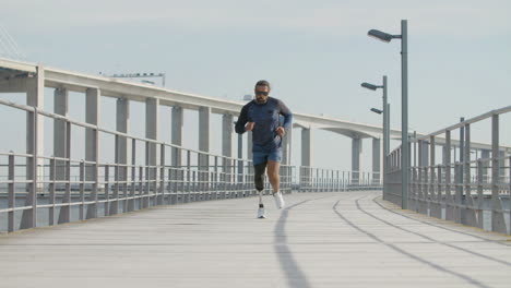 Focused-Sportsman-With-Artificial-Leg-Running-Along-Embankment-In-The-Morning
