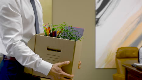 Close-Up-Of-A-Unrecognizable-Employee-Leaving-The-Office-With-His-Personal-Stuff-In-A-Box