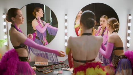 Female-Dancer-Using-Make-Up-While-Her-Colleagues-Are-Getting-Ready-For-The-Show